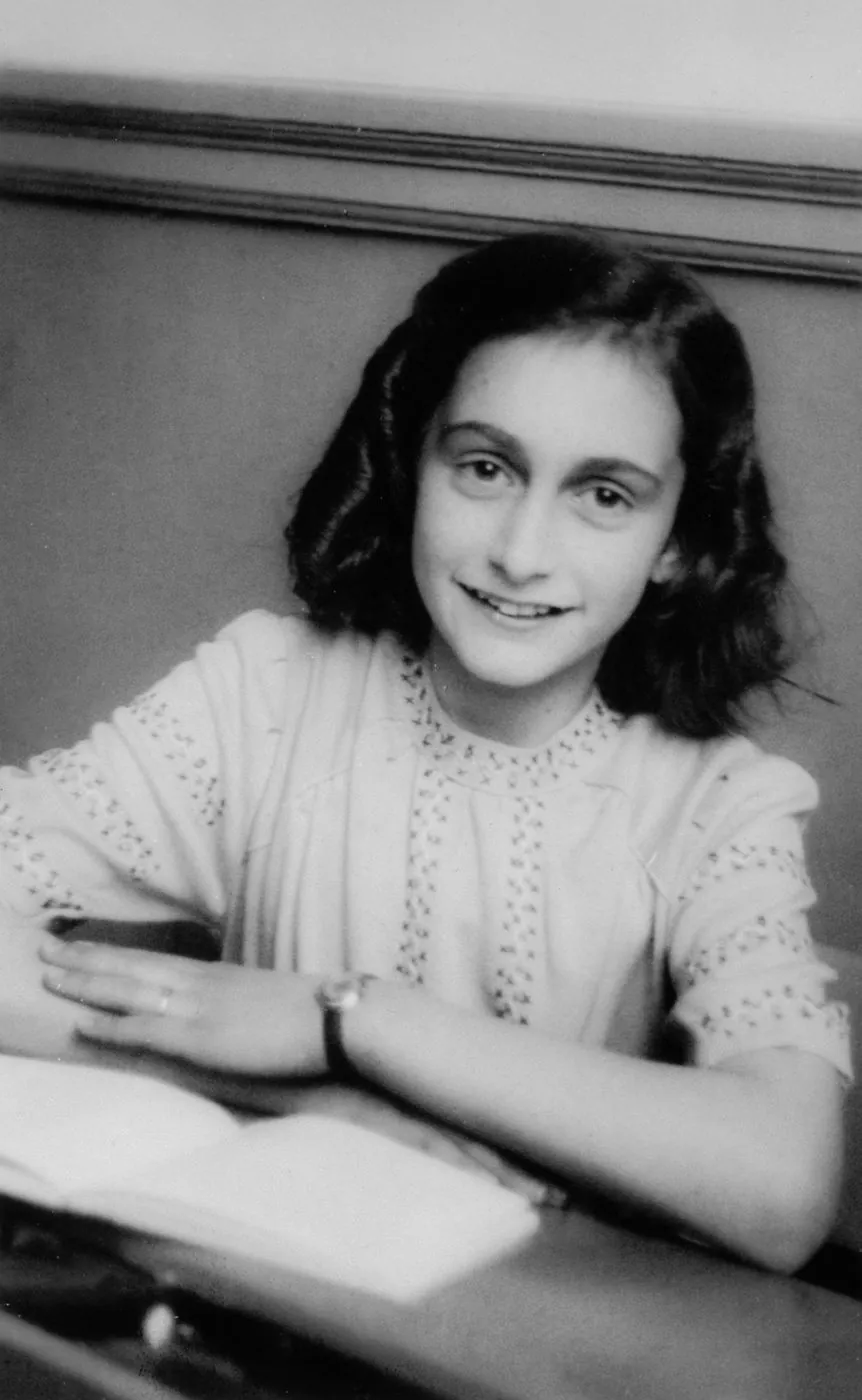 Photograph of Anne Frank smiling at her school desk, taken by a school photographer in December 1941 (Anne Frank House collection)
