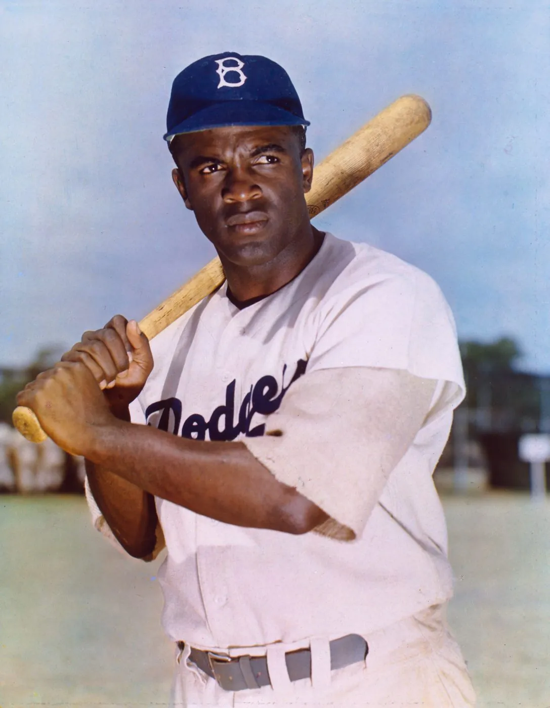 A color studio portrait photograph of Jackie Robinson in his Brooklyn Dodgers uniform